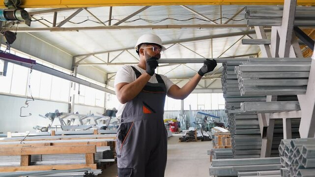 Metalworking Warehouse Indian Worker Arranging Metal Profiles and Square Tubes on Storing Shelves