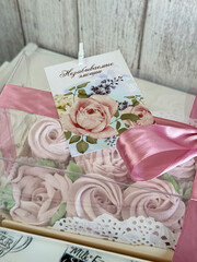 A box of homemade marshmallows. Tied with a ribbon. The tag has the inscription in Russian Unforgettable emotions. Flowers made of marshmallow.