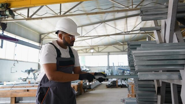 Metalworking Warehouse Indian Worker Arranging Metal Profiles and Square Tubes on Storing Shelves