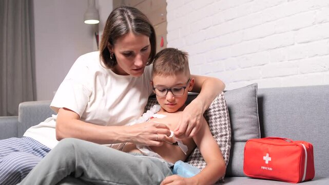 Mother applying electrodes of a holter monitor to her preteen son