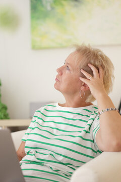 Blonde Frau am Laptop ist mit ihren Gedanken weit weg