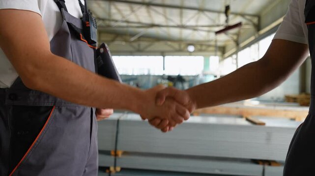 Handshake two diverse engineers on the background of a metal profile warehouse