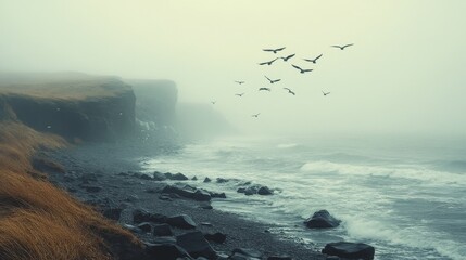 Foggy coastal landscape with birds flying above, waves crashing on the shoreline, and rocky cliffs covered in sparse grass