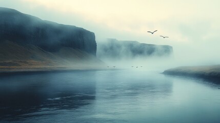 Naklejka premium Serene river flows between mist-covered cliffs, while birds soar gracefully in the cloudy sky above tranquil waters