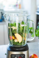 healthy green smoothie with apples, banana, spinach in glass on a kitchen background