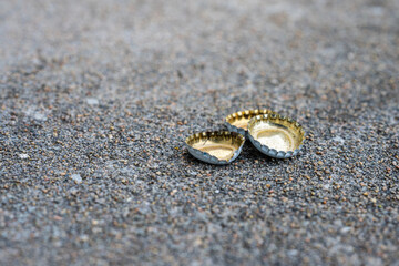 Small pile of bottle caps on asphalt.
