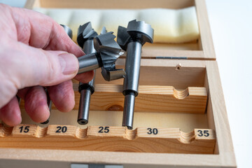 person holding one of a set of preciaion metal forstner bits for engineering and woodworking  in a...