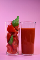 tomato juice in a glass glass and fresh tomatoes in a glass with basil