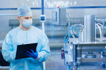 Concept med industry on medicine factory. Worker use clipboard for control quality on automatic...