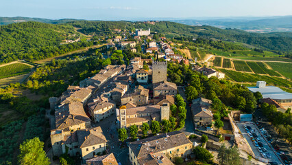 An aerial view of Castellina in Chianti, a picturesque town in Tuscany's renowned Chianti wine region, captured by a drone. Perched on a hill, Castellina in Chianti is surrounded by rolling vineyards 