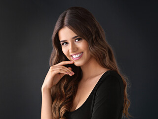 Fototapeta premium Portrait, smile and haircare for woman in studio, proud and texture of hair and treatment in salon. Black background, shine and strong hairstyle with cosmetics of model, person and hairdo in space