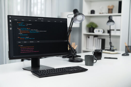 Programming code on computer screen desktop placing on working desk showing intelligent website development coder system running database online with information technology design concept. Infobahn.