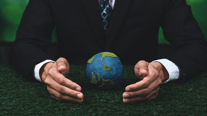 Businessman holding planet Earth globe symbolize eco-friendly business commitment to environmental protection and zero carbon emission. Earth World Day concept to promote eco awareness. Gyre © InfiniteFlow