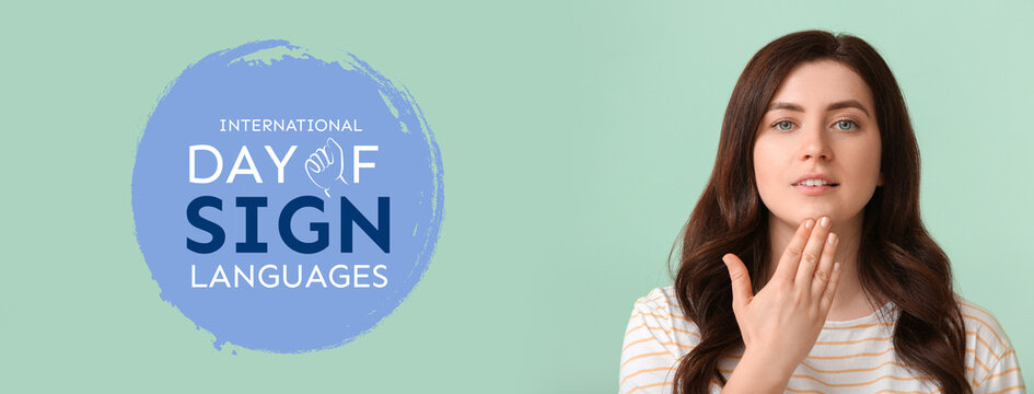 Young deaf mute woman using sign language on color background