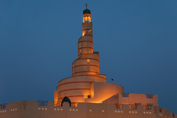 Al Fanar Building at night with blue sky which is one of the most famous landmarks in Doha, characterized by its spiral shape, and is located near Souq Waqif, Doha, Qatar shot take on ‎July ‎3, ‎2024. © Salim