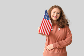 Young woman with USA flag on grey background