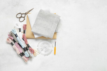 Different canvases with scissors, mouline threads and ball pins on grunge white background