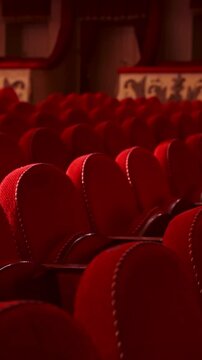 Rows of empty red velvet seats inside a theater or opera. No people in hall because of pandemic. Selective focus on opera interior. Vertical video