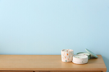 Holders with candles on table near blue wall in room