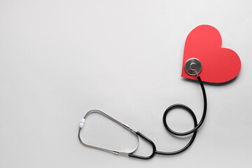 Stethoscope and red heart on light background.  Cardiology concept