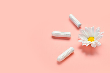 Composition with menstrual tampons and chamomile flower on coral background, closeup