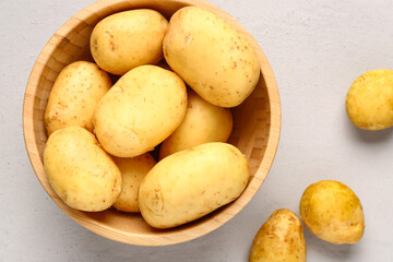 Wooden bowl with raw baby potatoes on grey background