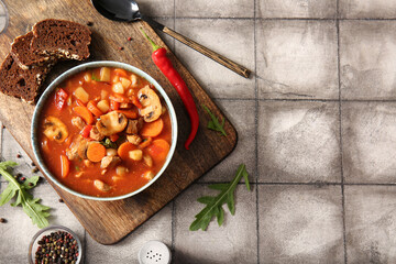 Bowl of tasty beef stew on grey tile background