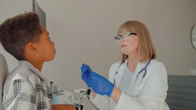 Kid sitting in ent chair and opening mouth for examination