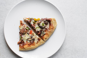Overhead view of chicken pizza slices on a white plate, top view of beef and mushroom pizza slice