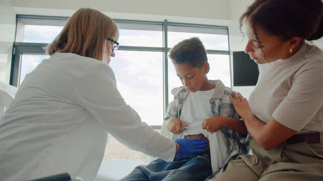 Shy kid raising tshirt and showing stomach area to doctor