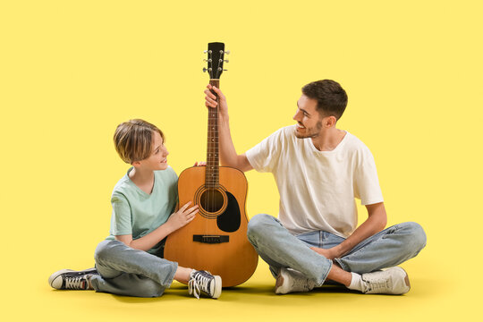 Private music teacher and little boy with guitar sitting on yellow background