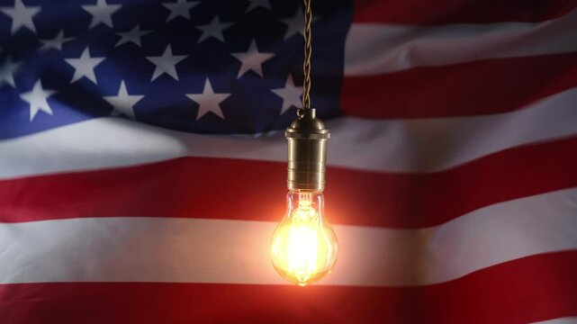 Classic antique Edison Tungsten filament lamp on waving american USA flag background. Creative idea, realization, discovery, eureka