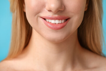 Smiling young woman with beautiful lips on blue background, closeup