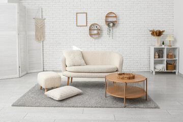 Interior of white loft style living room with cozy sofa, pouf and coffee table