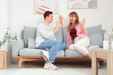 Young couple with hearing aid on sofa at home