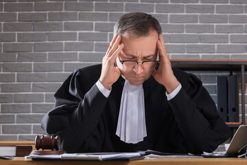 Tired mature judge working at table in dark office