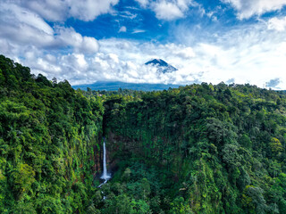 Panorama of the Kapas Biru waterfall in East Java, Indonesia. In the distance there is a jungle and...