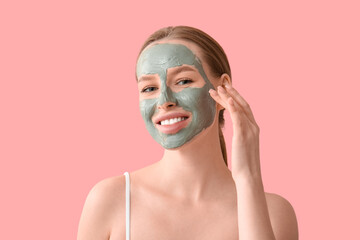 Beautiful young woman with facial mask on pink background