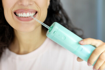 Woman using oral water irrigator, cleaning teeth with modern equipment, closeup. Dental oral care...
