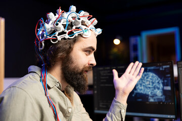 Smiling software technician using EEG headset to upload consciousness into computer. Happy IT admin...