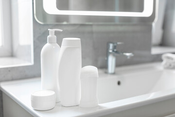 Set of different bath personal care products on white washbasin in bathroom, mockup for brand...
