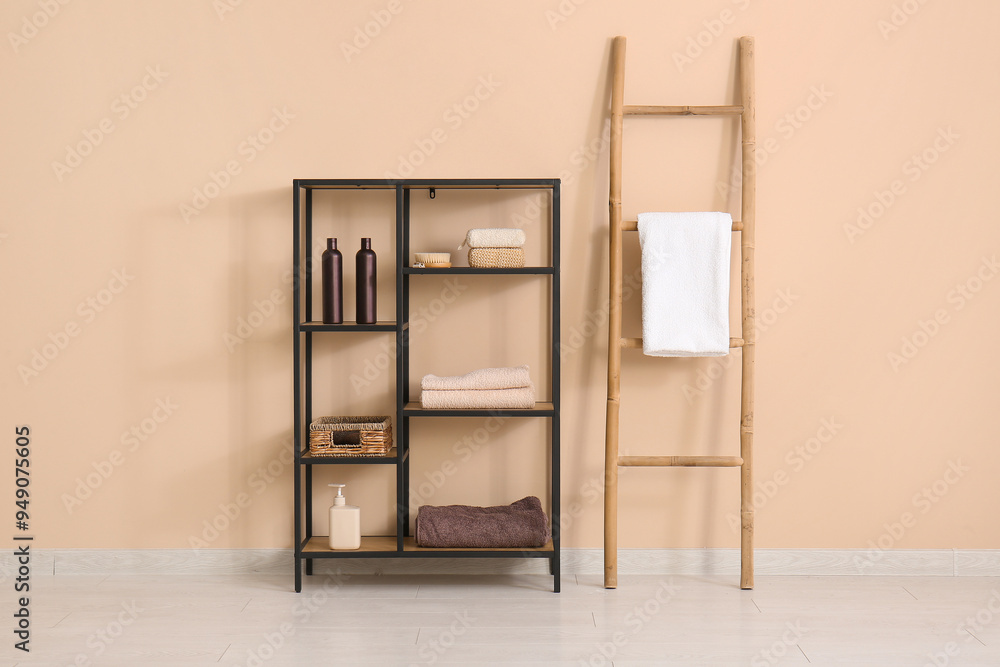 Sticker shelving unit with towel and bath accessories near beige wall