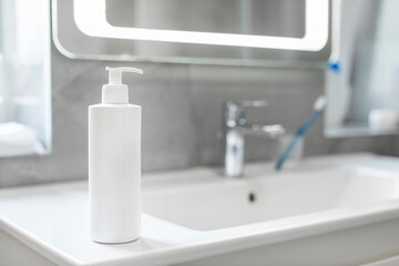 White lotion cosmetic bottle on basin in bathroom closeup, cosmetic mockup for brand design. Personal care product