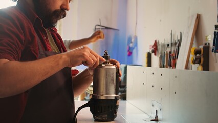 Serviceman in furniture assembling shop changing rotor part on spindle moulder machinery. Engineer...