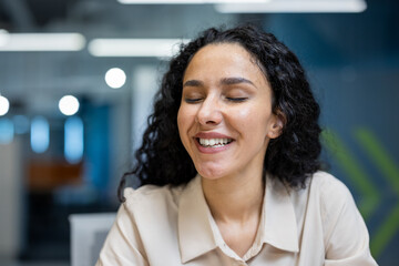 Portrait of joyful woman smiling with closed eyes, expressing happiness and contentment in bright...