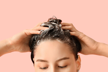 Naklejka premium Beautiful young woman washing her hair with shampoo on pink background, closeup