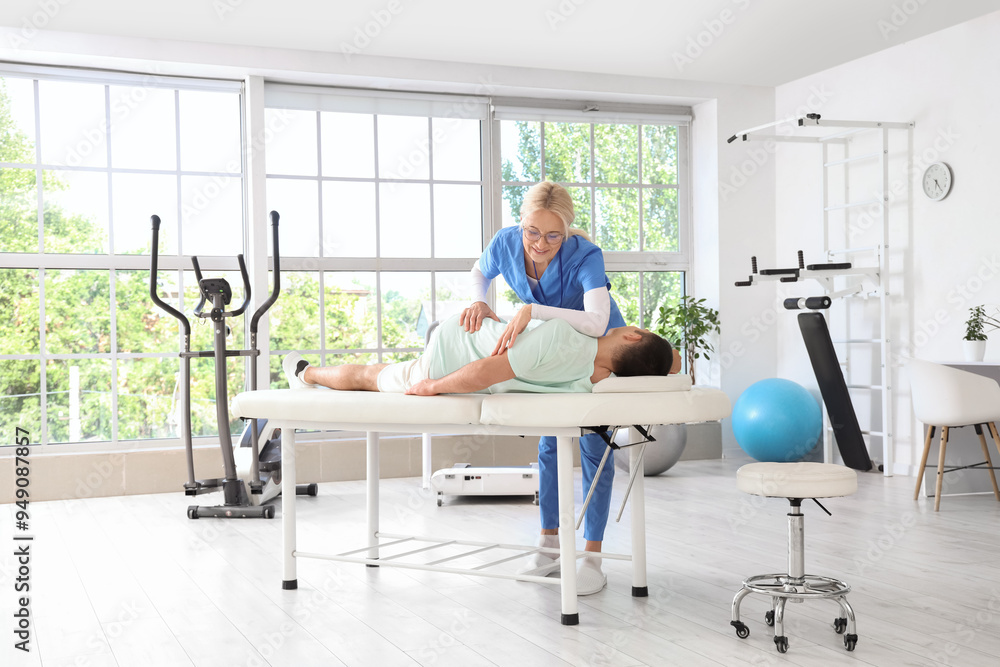 Sticker female physiotherapist working with young man on couch in rehabilitation center