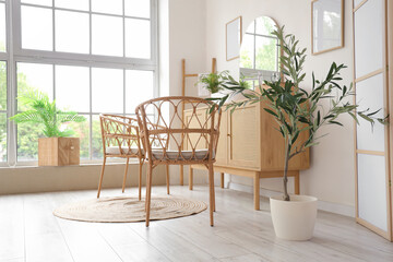 Wicker chairs and wooden chest of drawers in interior of modern bathroom