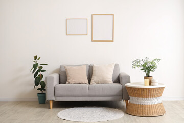 Beautiful living room with soft sofa, pillows, houseplants and coffee table