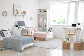 Interior of dorm room with beds, tables and moving boxes